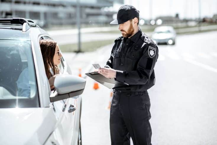 Policial multando uma mulher dentro de um carro