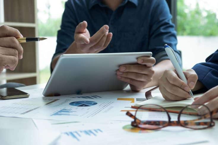 Gestores analisando dados para praticar a governança corporativa.
