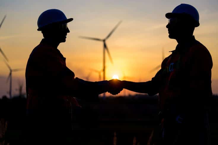 Técnicos trabalhando ao ar livre no campo de turbinas eólicas.
